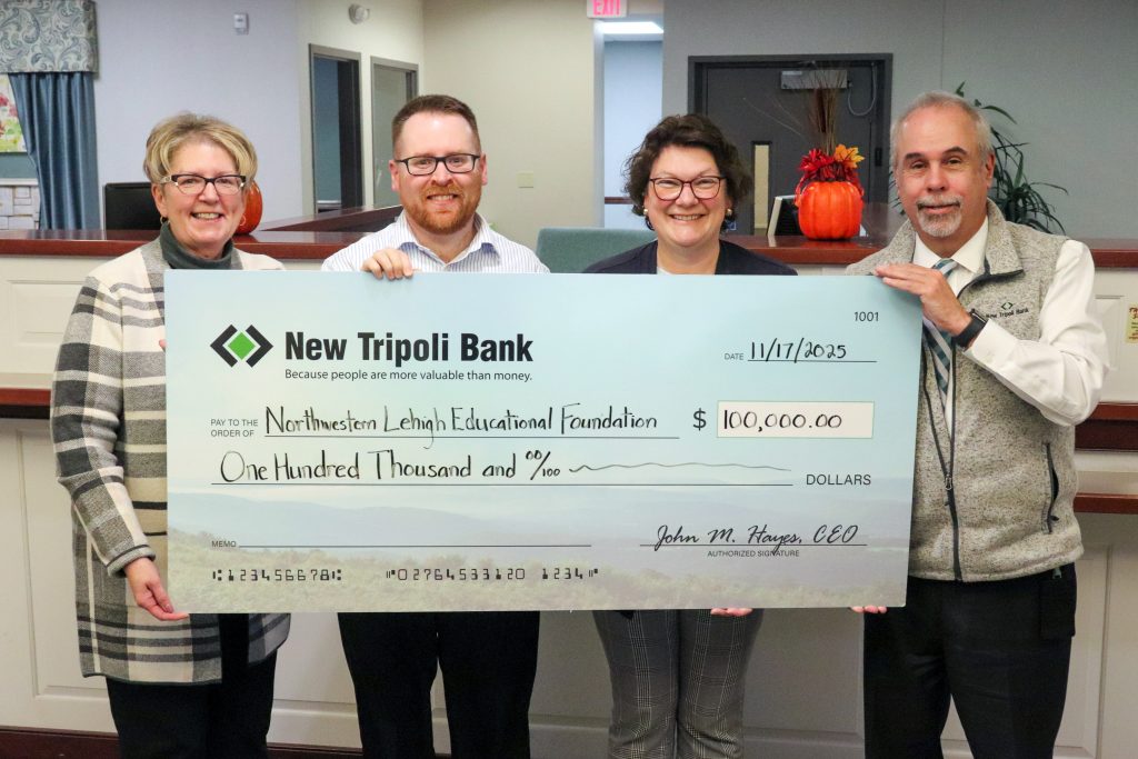 Photo of four people standing with a large check.