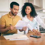 Couple, insurance paperwork and budget planning with laptop, bills and finance with taxes and mortgage. Financial documents, payment and loan with policy, audit and review with asset management